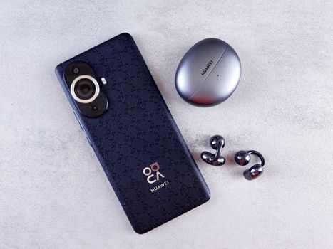 Stylish smartphone with case and metallic earphones on a textured gray background.