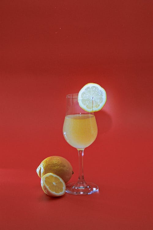 A glass of wine with a lemon slice on a red background