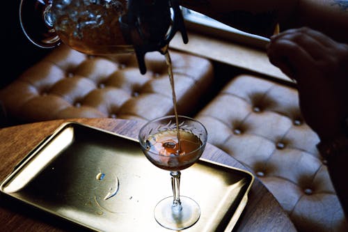 A person pouring a drink into a glass on a tray