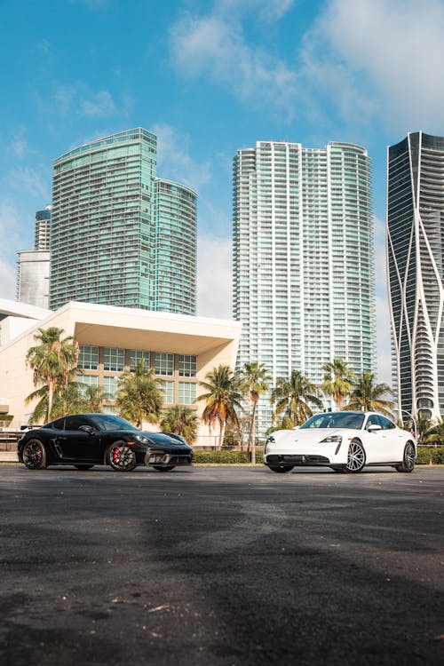 Two white sports cars parked in front of a city