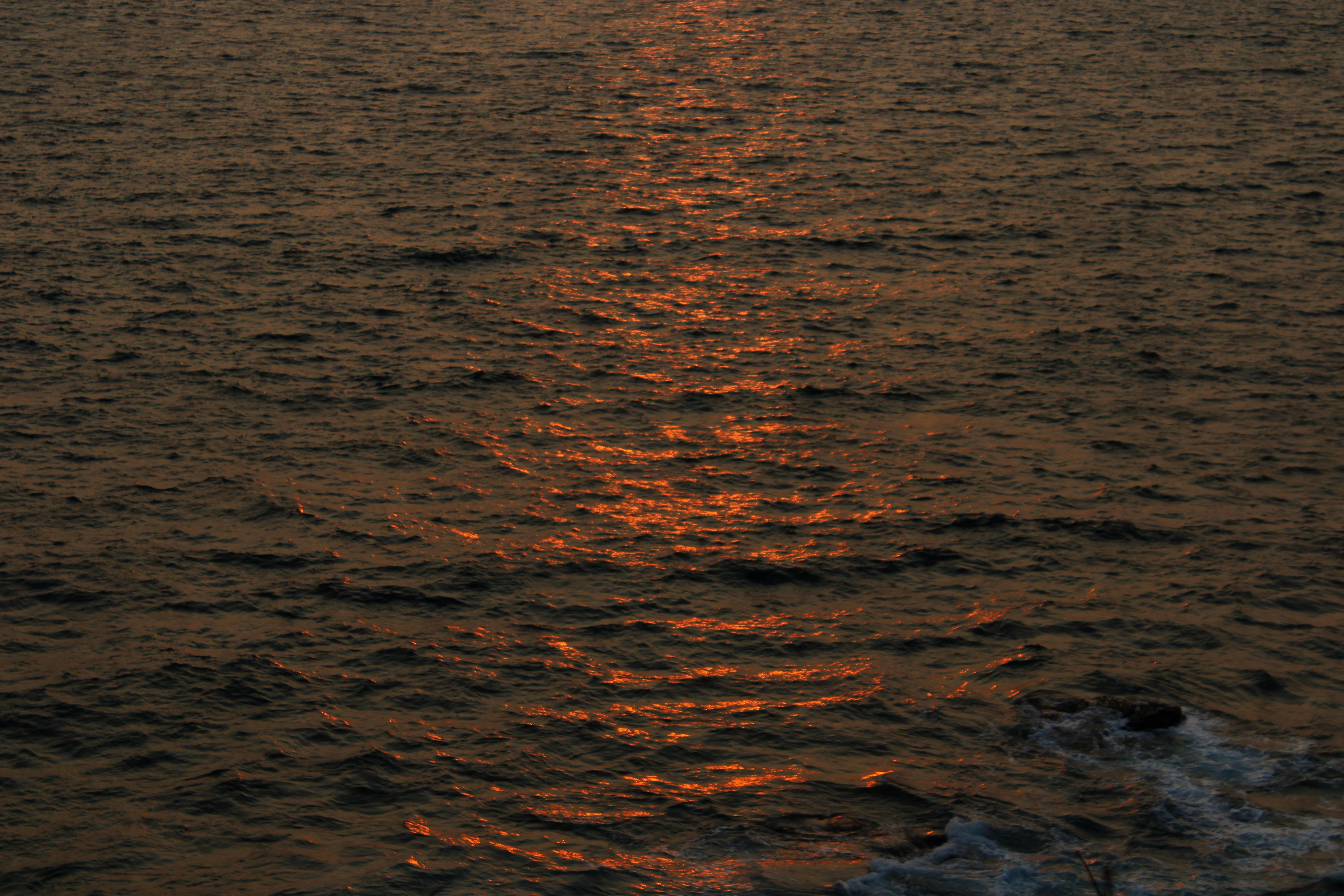 A breathtaking view of ocean waves reflecting the vibrant hues of a sunset.