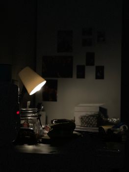 A mysterious and quiet desk setting illuminated by a lamp, creating a moody atmosphere.