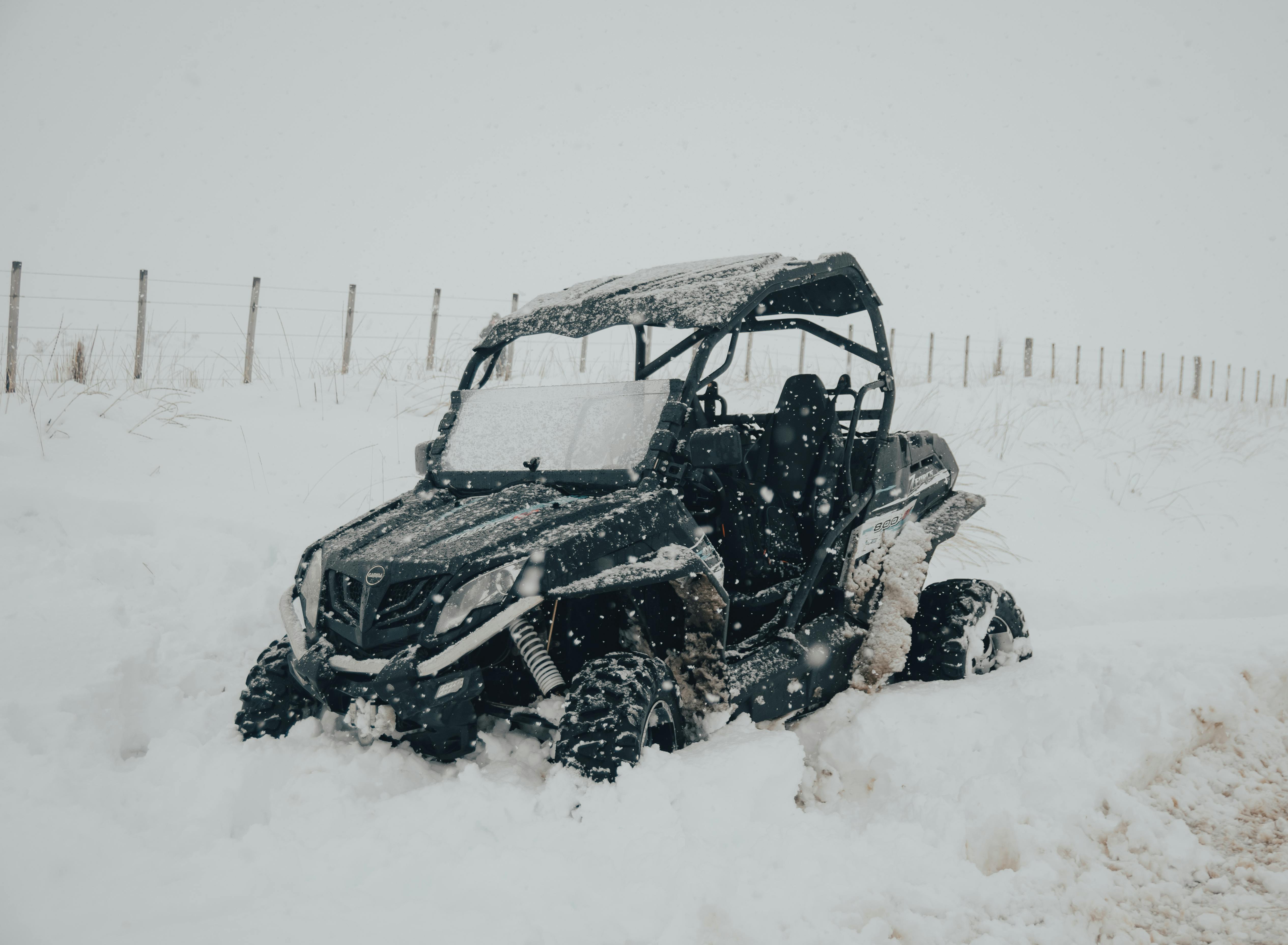 An ATV vehicle stuck in heavy snow during a winter day with snowfall.