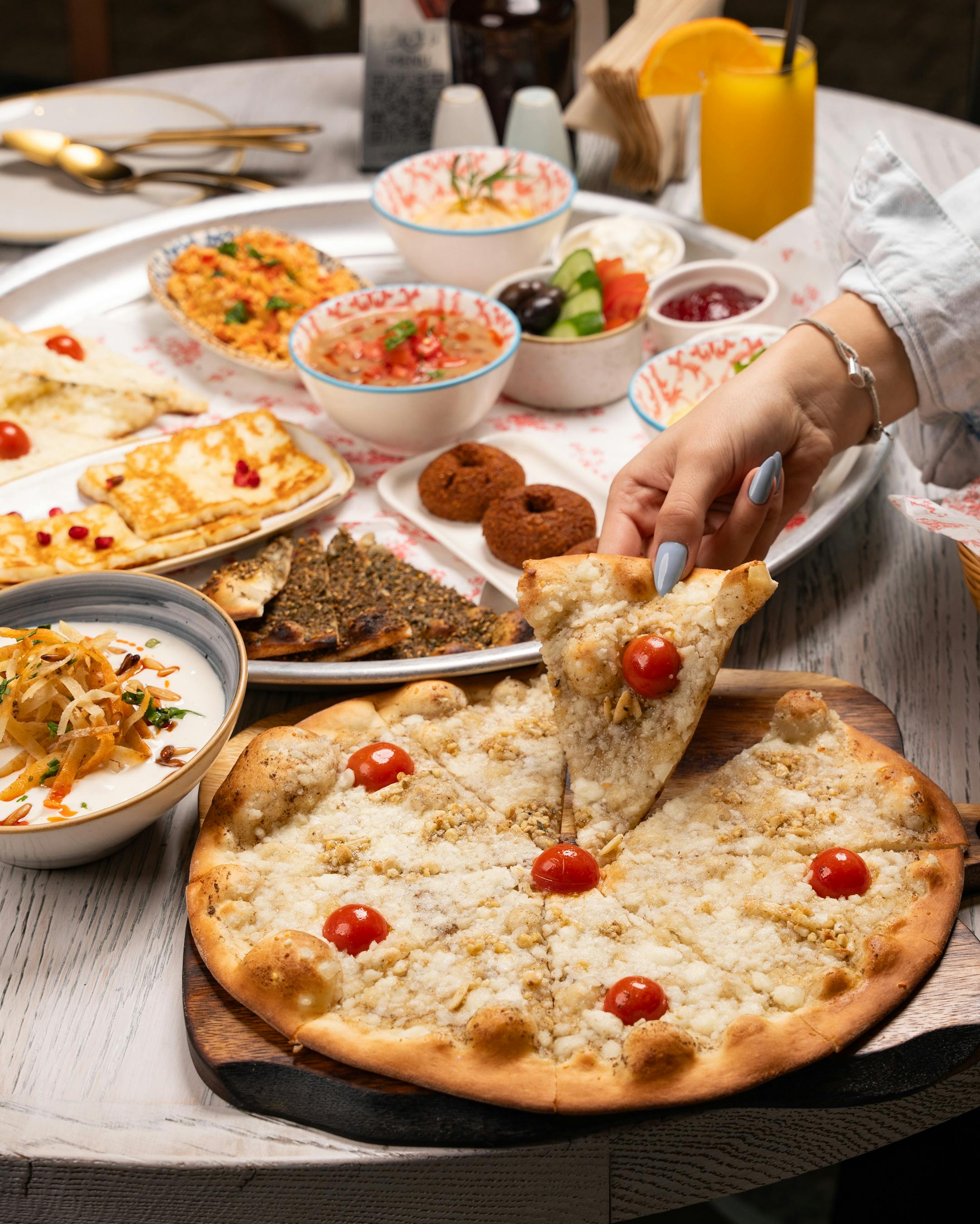 An abundant spread of Middle Eastern dishes with flatbread and dips, enjoyed by a woman.