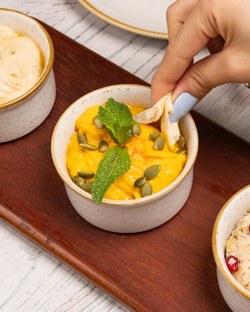 A person is holding a piece of food in a bowl