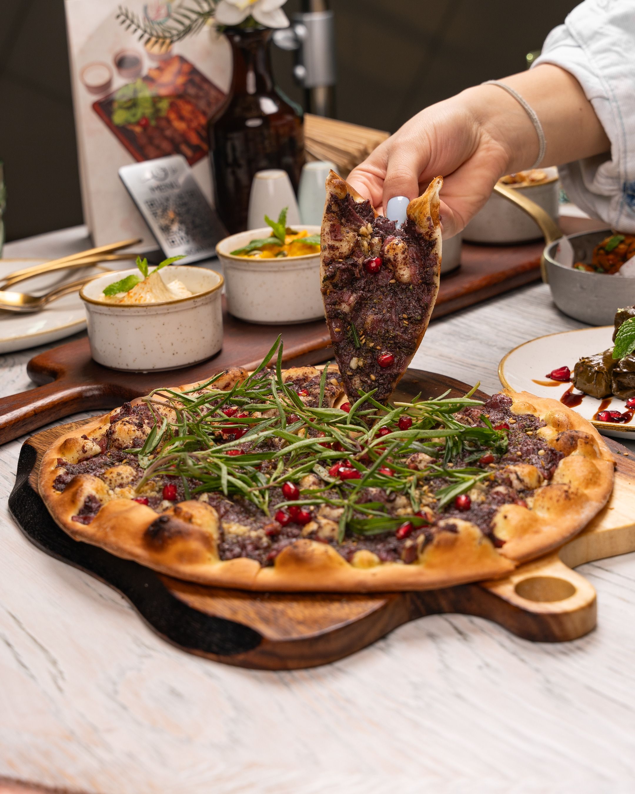 Delicious Lebanese flatbread topped with greens and pomegranate, served on a wooden board.
