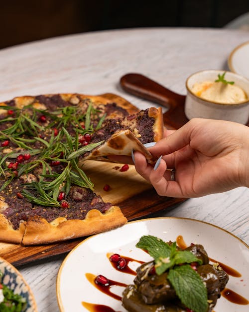 A person is holding a slice of pizza on a plate