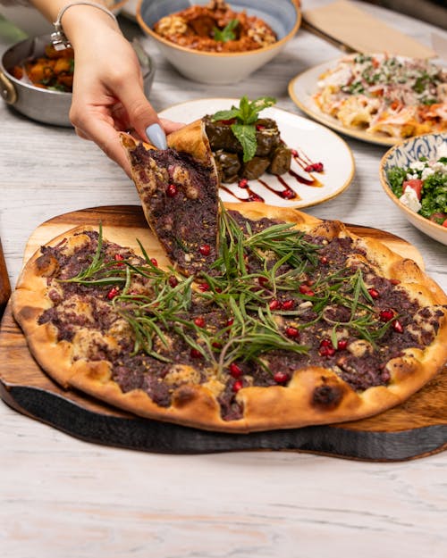 A person is holding a slice of pizza on a wooden table