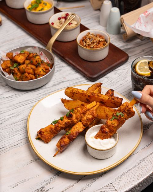 Free Grilled skewers and potato wedges with dipping sauce on a wooden table. Stock Photo