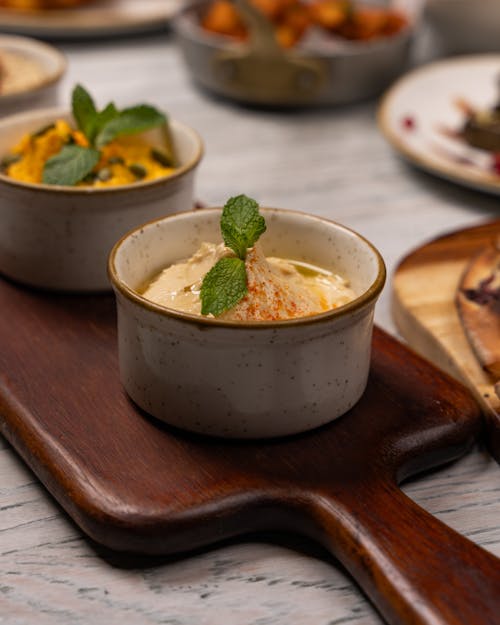 A wooden tray with three bowls of food on it