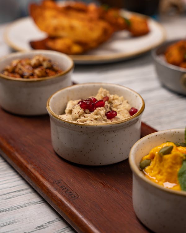 A wooden tray with three bowls of food on it