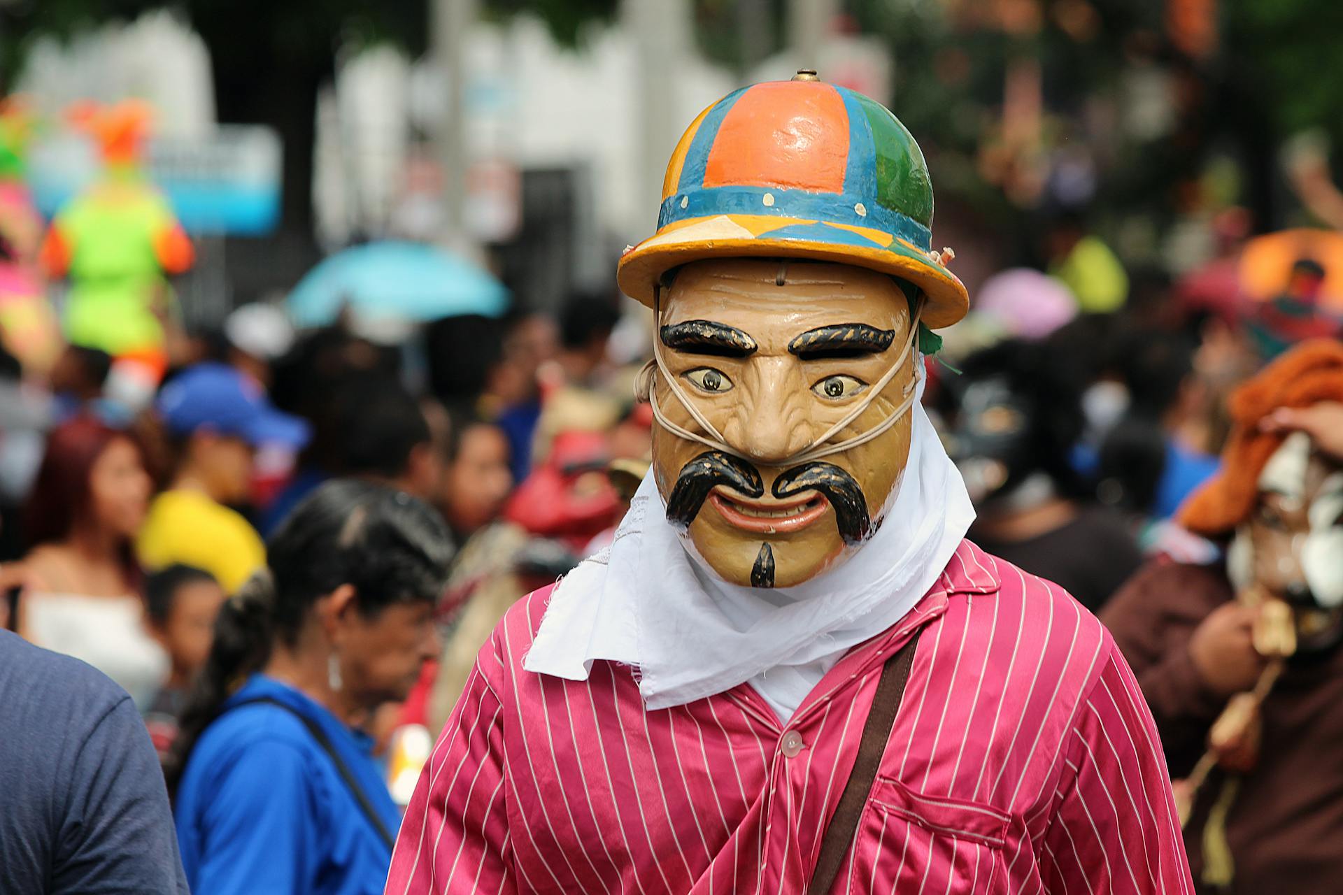 Vibrant street festival in San Salvador featuring masks and costumes amidst a lively crowd.