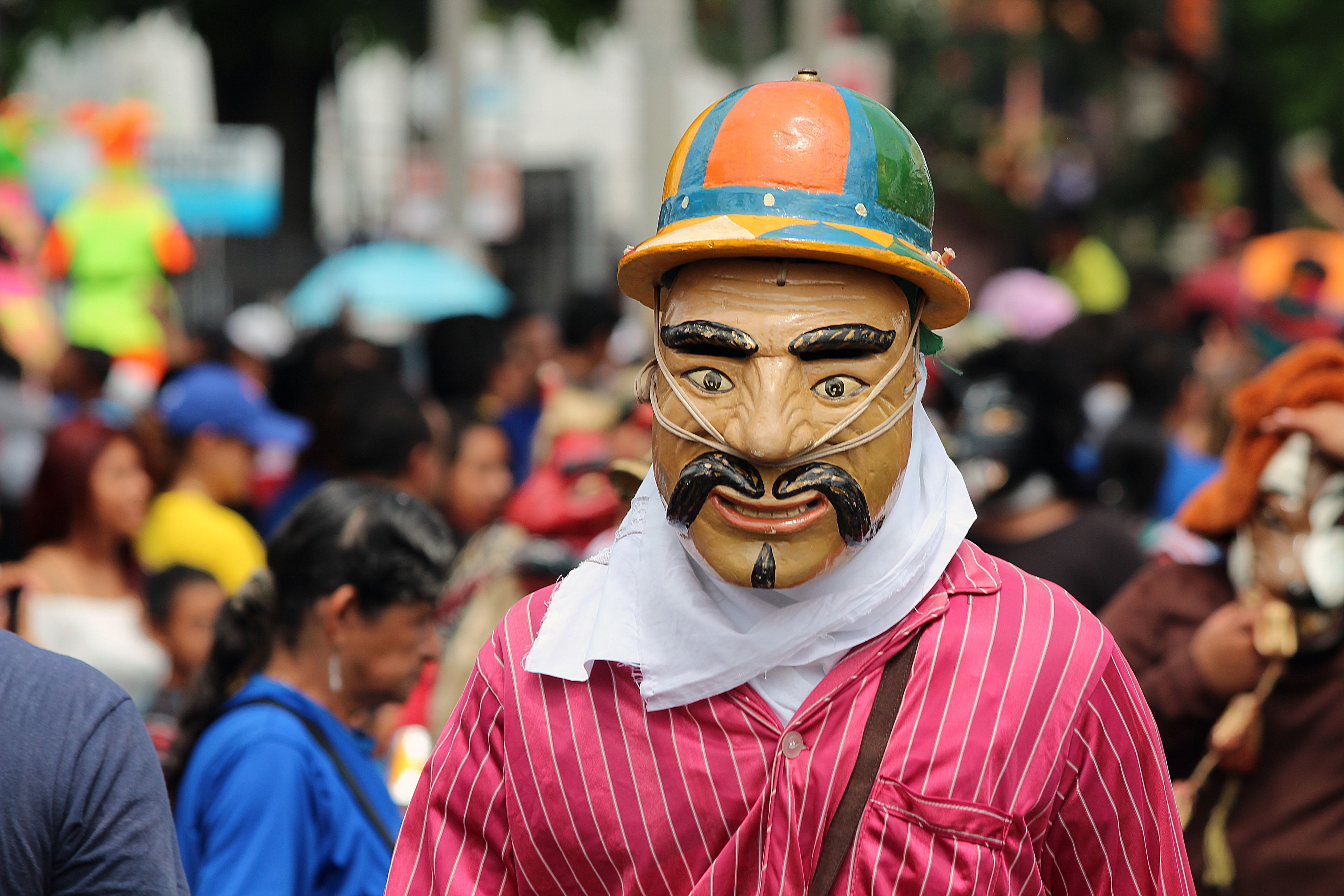 Vibrant street festival in San Salvador featuring masks and costumes amidst a lively crowd.