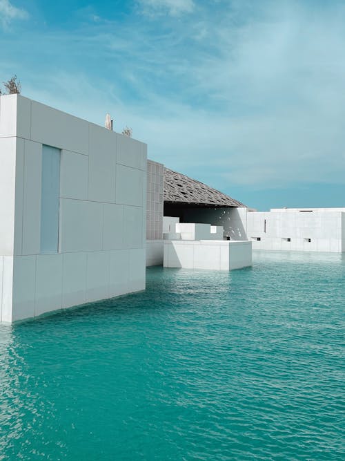 A white building with a blue roof sitting in the water