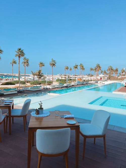 A pool with tables and chairs near the ocean