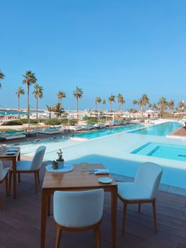Elegant dining setup poolside at a luxurious Dubai resort with palm trees and blue skies.