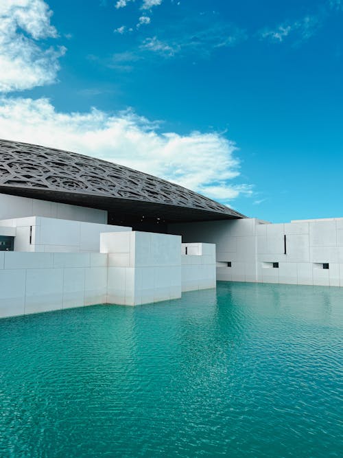 The building is made of white stone and has a large pool