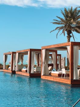 Elegant wooden cabanas by a serene pool at Saadiyat Beach Club, offering luxury and relaxation.