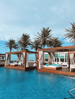 Elegant cabanas by the pool with palm trees at Saadiyat Beach Club, Abu Dhabi.