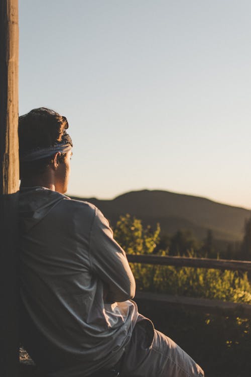 Free A man sitting on a bench looking out at the sunset Stock Photo