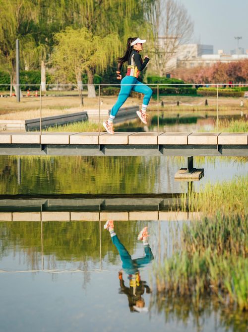 Free Woman jogging on bridge with vivid reflection in the pond below. Stock Photo