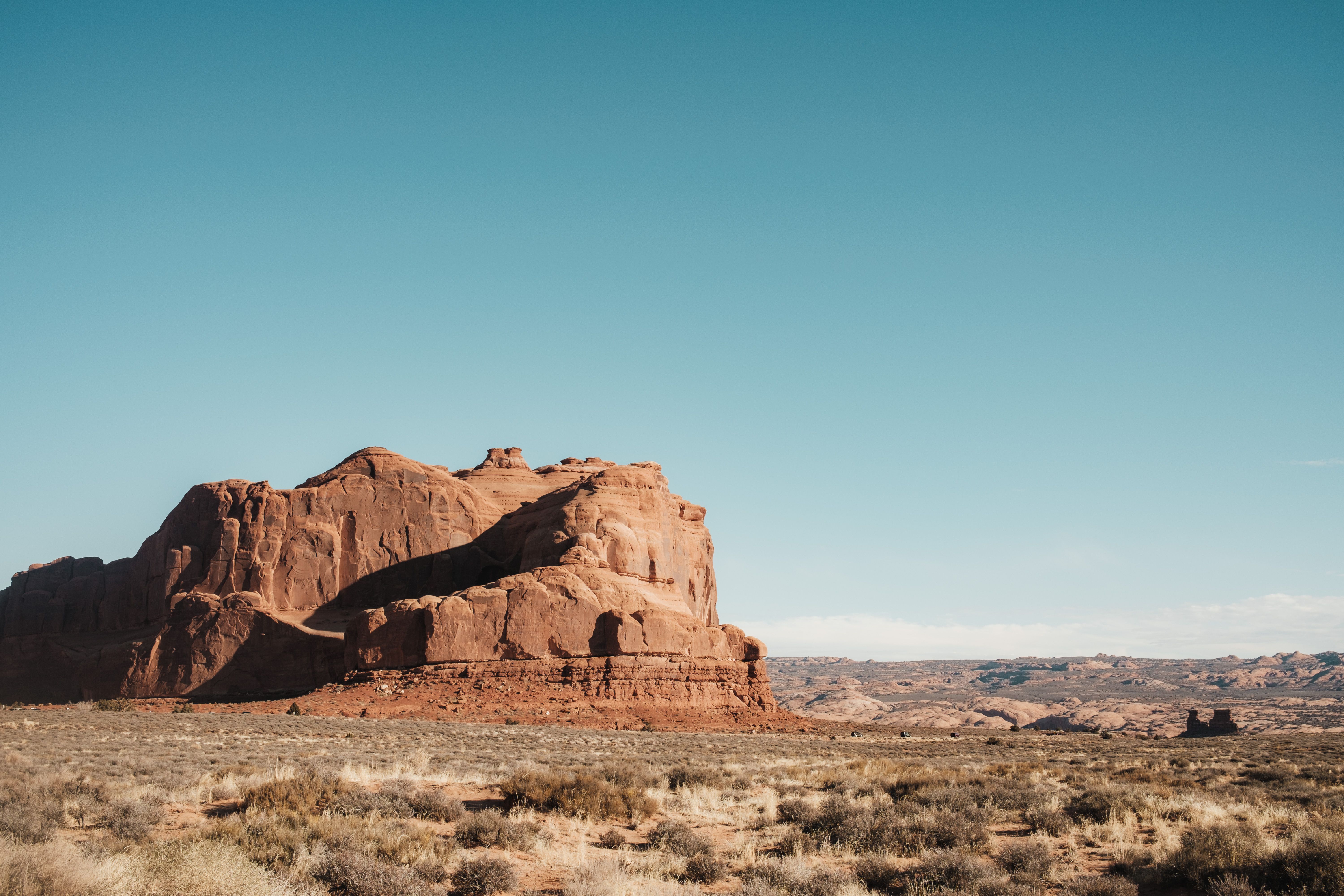 A desert landscape with a large rock formation · Free Stock Photo