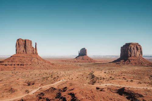 Free A breathtaking view of Monument Valley's iconic mesas under a clear blue sky. Stock Photo