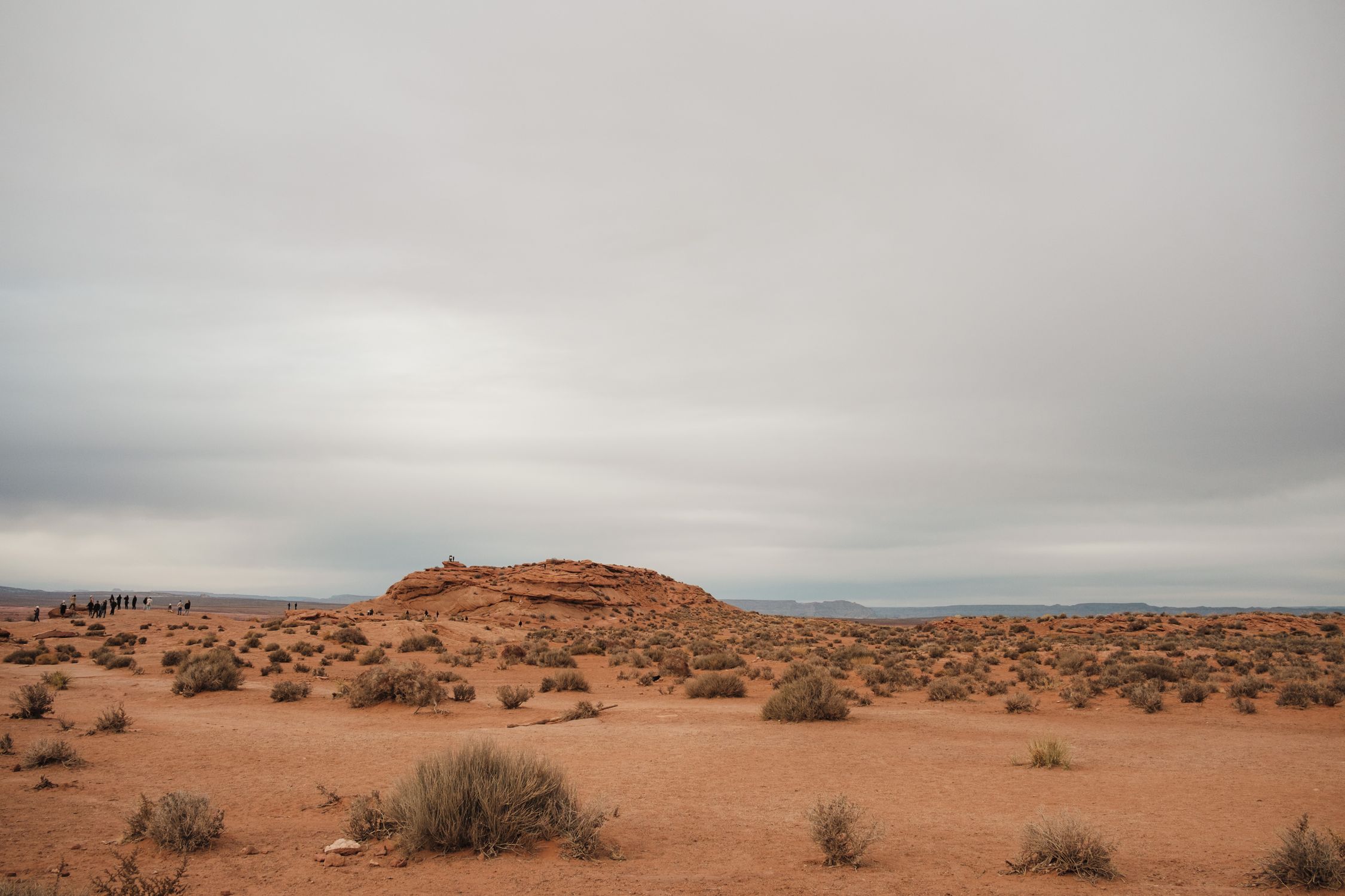 A cloudy desert landscape near Page, Arizona, showcasing rocky formations and sparse vegetation.