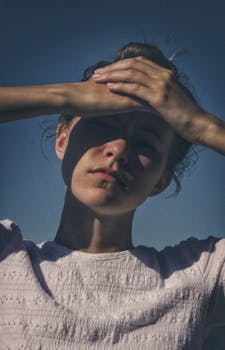 一位女性用手遮挡阳光，在脸上投下戏剧性的阴影