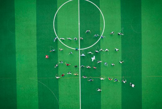 Top view of a group exercising with jump ropes on a vibrant green sports field.