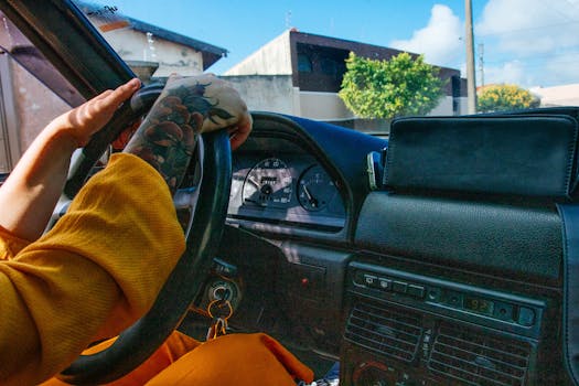 特写镜头中，一位有纹身的人驾驶着一辆仪表板彩色的古董车