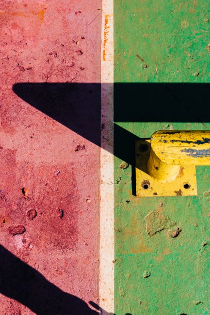 A vibrant abstract view of a rusted surface with colorful paint and dramatic shadows.