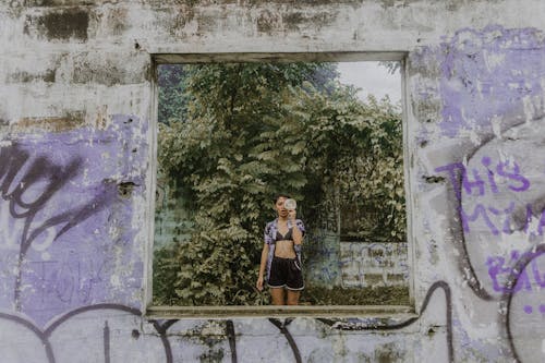 A woman standing in front of a window with graffiti on it