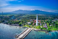 从空中俯瞰，印度尼西亚万丹的灯塔和海岸线被郁郁葱葱的绿色植被和山脉所环绕，景色令人惊叹