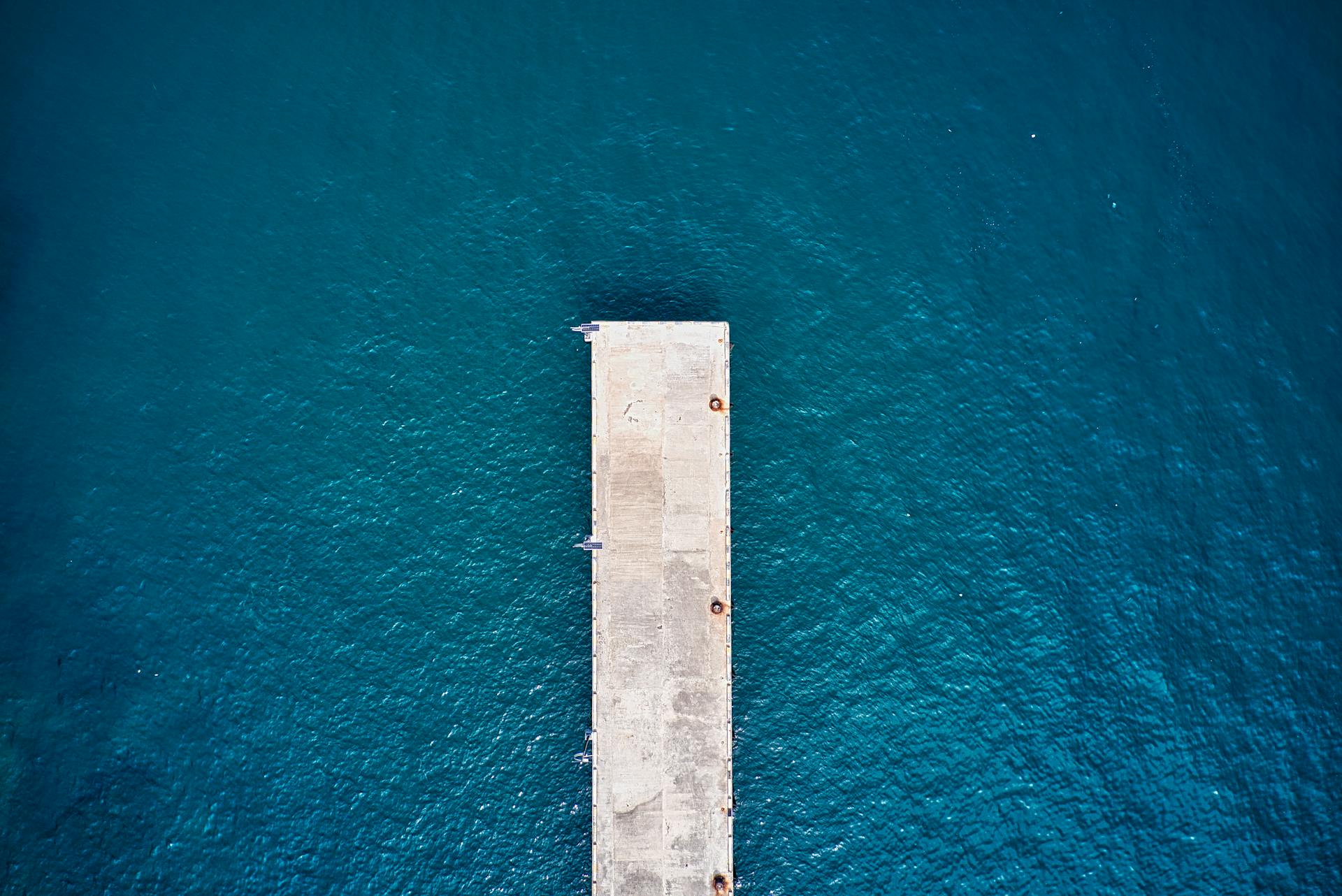 Bird's eye view of a concrete dock extending into deep blue waters in Banten, Indonesia.