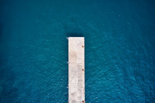 Free Bird's eye view of a concrete dock extending into deep blue waters in Banten, Indonesia. Stock Photo