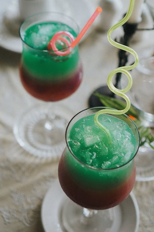 Two drinks with green and red colored drinks