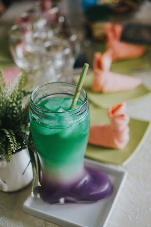 A green drink with a straw and a green plant