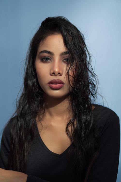 Free Studio portrait of a woman with long dark hair and a blue background, exuding elegance. Stock Photo