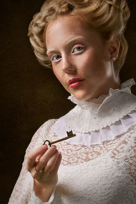 Portrait of a Victorian woman in lace holding an antique key.