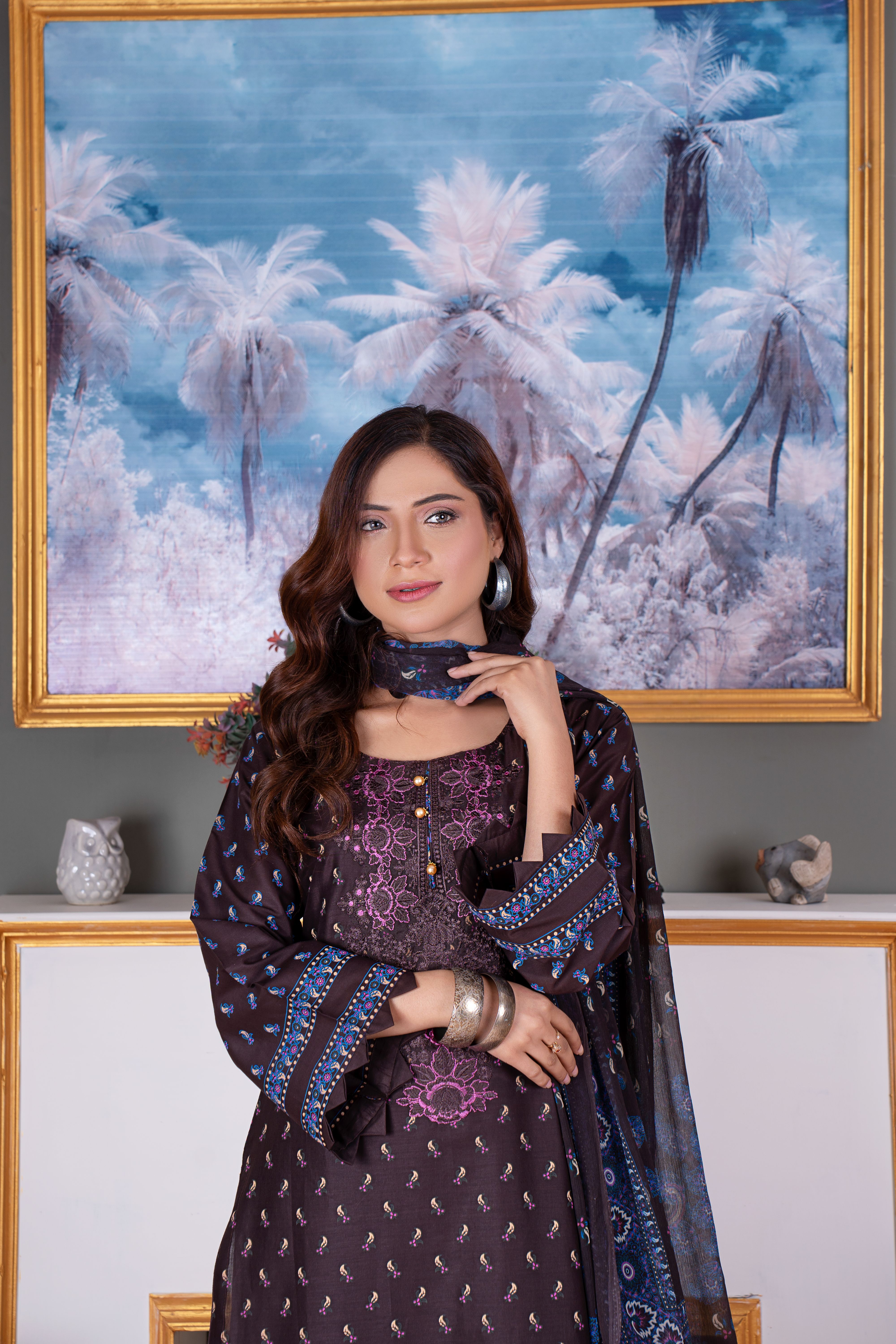 Portrait of a woman in traditional attire, posing in front of a scenic painting.