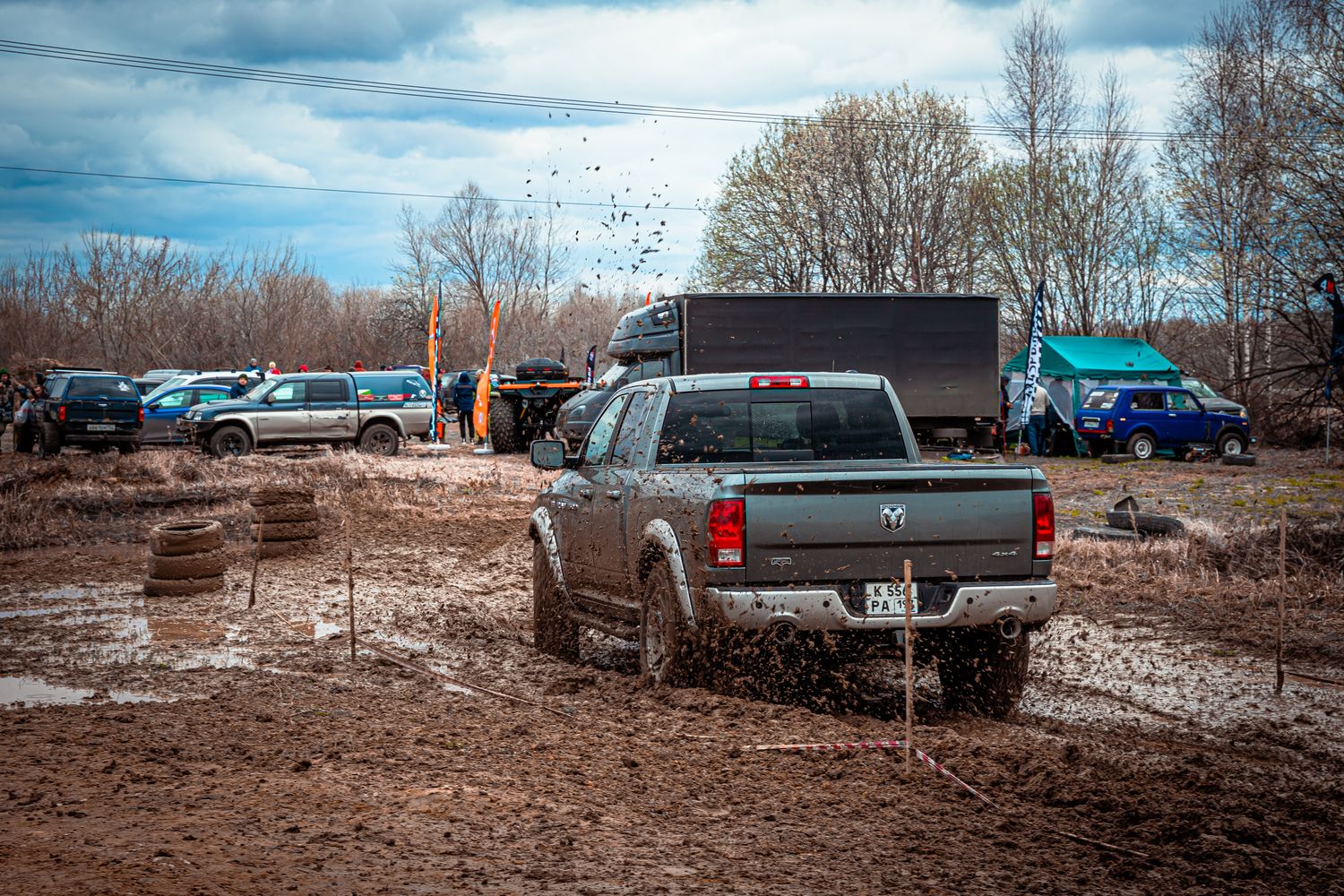 Pickup truck on aggressive mud-terrain tires churning through a deep mud pit off-road