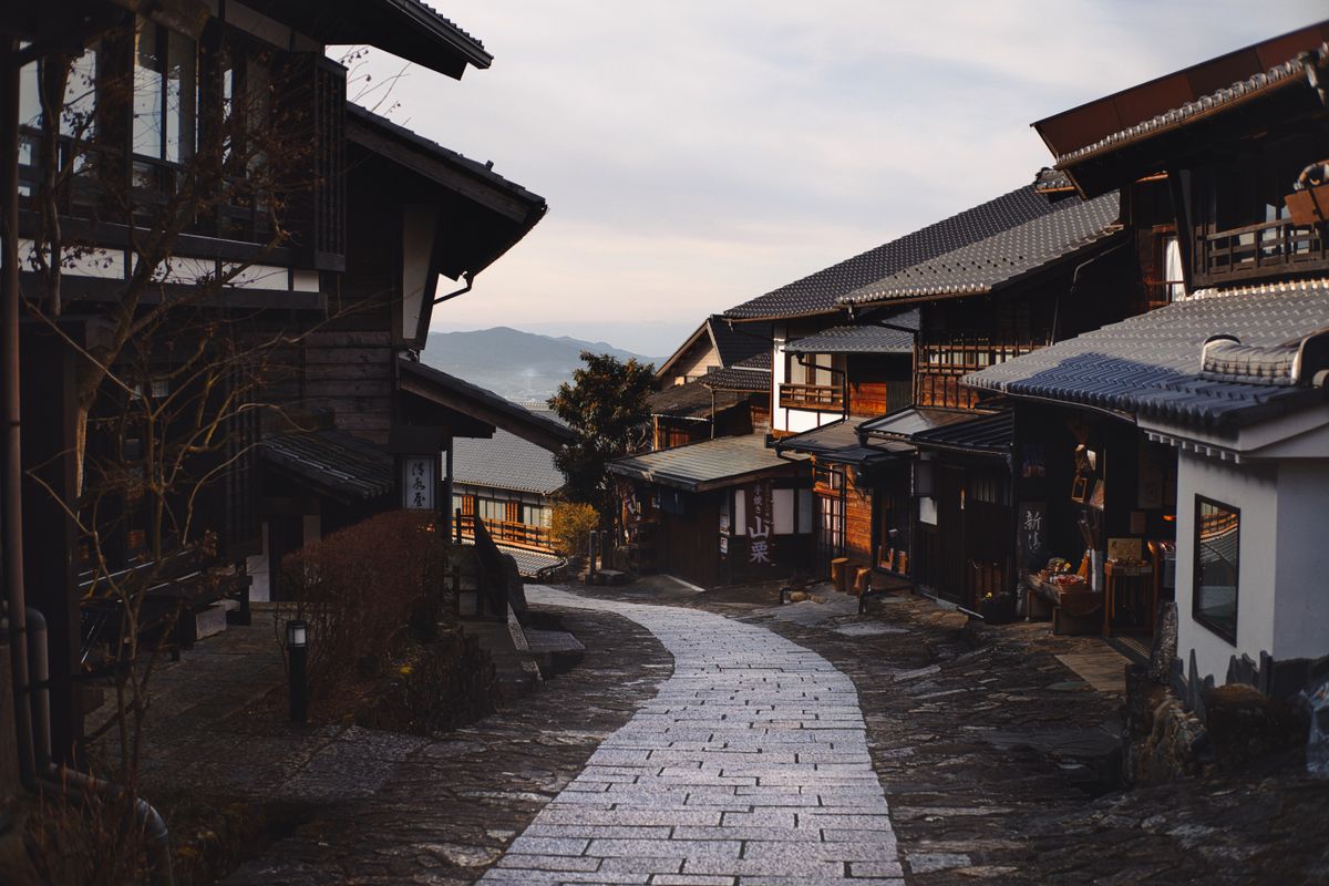 Stone-paved historic street between traditional timber buildings at dusk — the Edo-period merchant district atmosphere of Gifu's historic towns