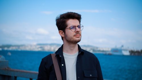 Free Fashionable man wearing glasses standing by the seaside in a casual look. Stock Photo