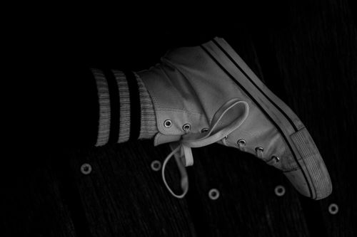 Free Black and white close-up of a sneaker and striped sock on wooden surface in Hamburg. Stock Photo