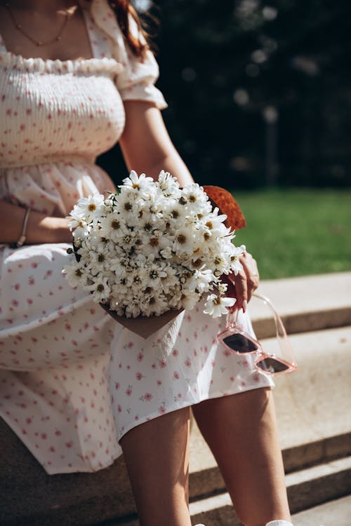 A woman holding a bouquet of flowers on a bench