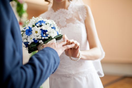 Free Woman Putting Ring on Man's Finger Stock Photo