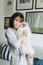 一位亚洲妇女在舒适的家中，亲切地抱着一只毛茸茸的波斯猫