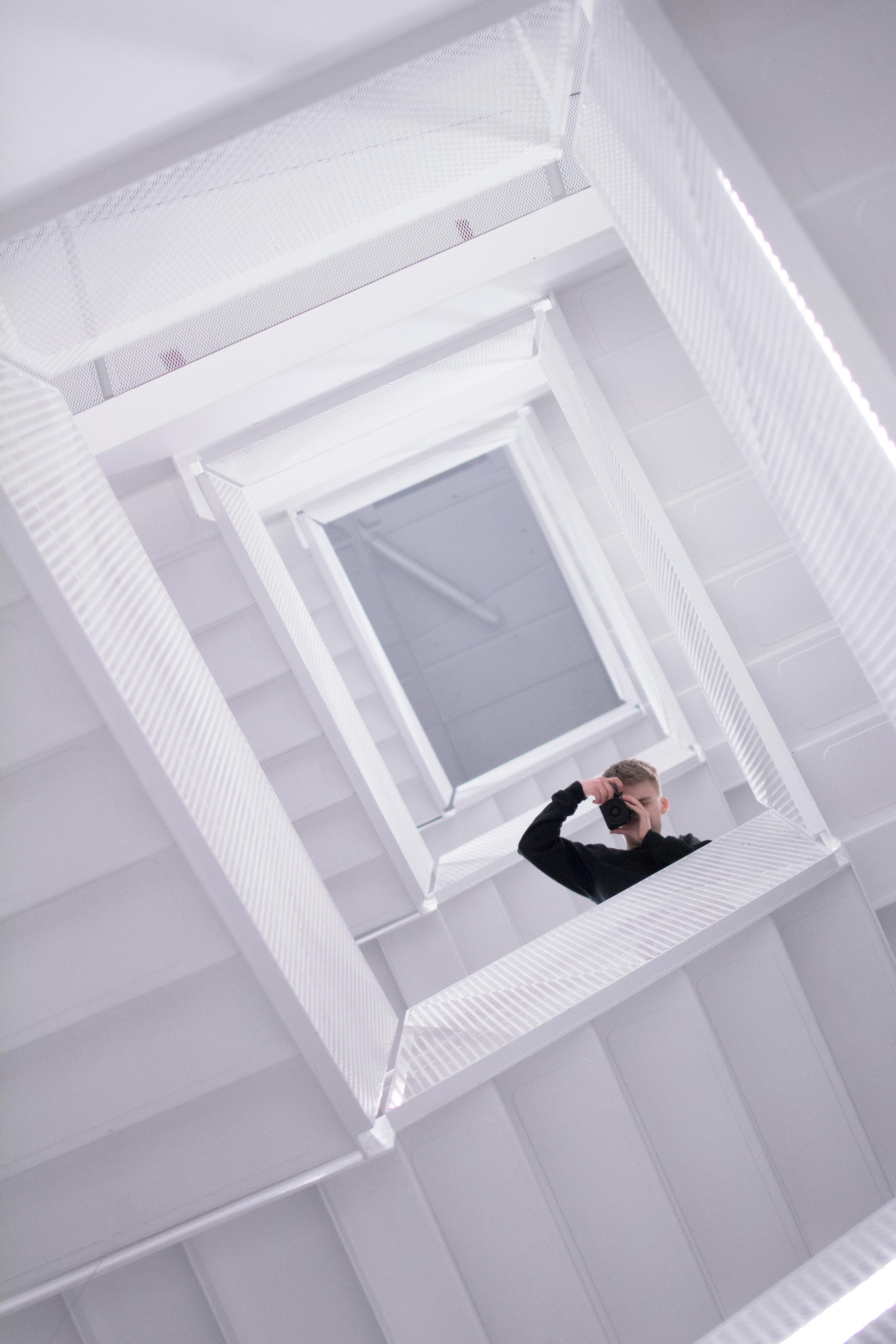 极简主义环境中，螺旋楼梯上一个人向上攀爬的戏剧性景象