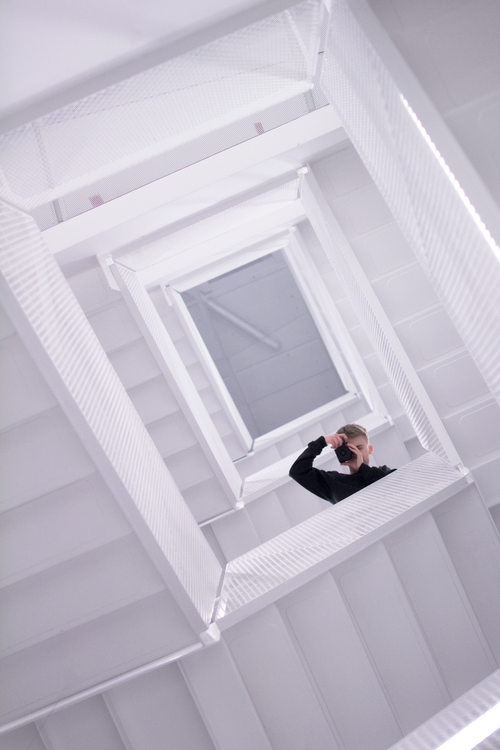Free Dramatic upward view of a person on a spiral staircase in a minimalist setting. Stock Photo